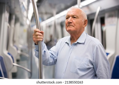 Senior Man Holding Handrail While Standing Inside Subway Train.