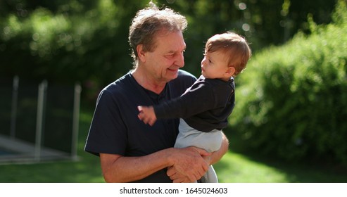 
Senior Man Holding Infant Baby Outside. Grand Father Bonding With Toddler Outdoors