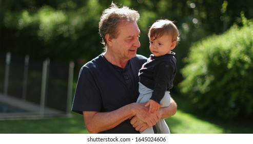 Senior Man Holding Infant Baby Outside. Grand Father Bonding With Toddler Outdoors