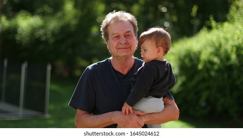 
Senior Man Holding Infant Baby Outside. Grand Father Bonding With Toddler Outdoors