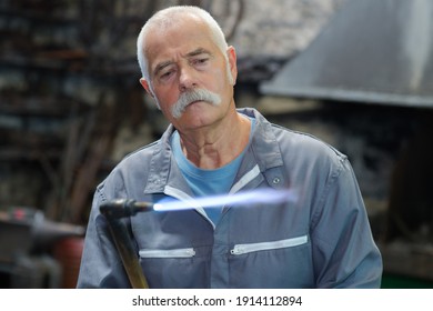 Senior man holding lit gas torch - Powered by Shutterstock