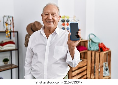 Senior Man Holding Smartphone At Retail Shop Looking Positive And Happy Standing And Smiling With A Confident Smile Showing Teeth 