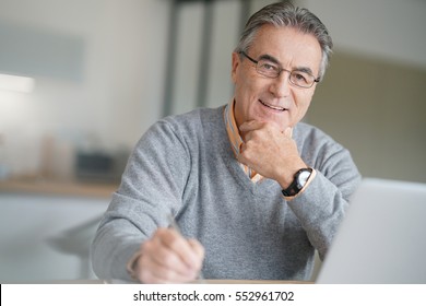 Senior Man At Home Connected On Laptop Computer