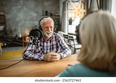 senior man host interviewer ask woman guest questions while record podcast
