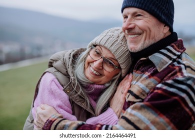 Senior Man Hugging And Consoling His Wife Outdoors In Garden In Winter.