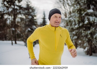 Senior Man Jogging Alone In Winter Forest.