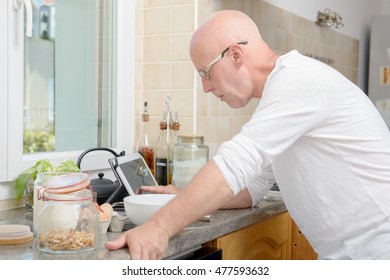 a senior man in kitchen using digital tablet 