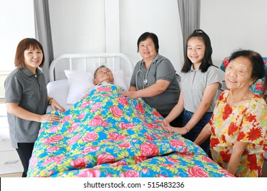 A Senior Man Laying On A Hospital Bed And Answering To His Doctor's Questions, Family Member Visit Around Bed, Asian Family Worry. 80s Man