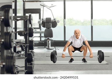 Senior man lifting a barbell at a gym - Powered by Shutterstock