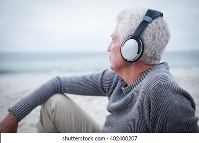 Senior man listening to music on headphone at beach - Powered by Shutterstock