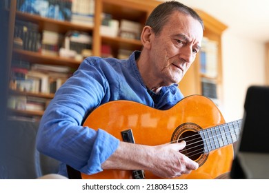 Senior Man Listening To Online Classical Guitar Lesson