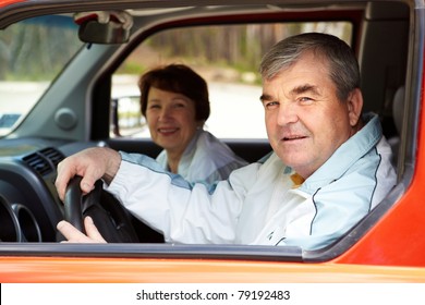 Senior Man Looking At Camera In The Car With His Wife On Background