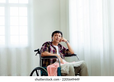 Senior Man Looking At The Camera While In A Wheelchair. An Old Asian Man Is Home Alone In A Wheelchair. Elderly Concept Asian Old Man Medical Health Help The Elderly