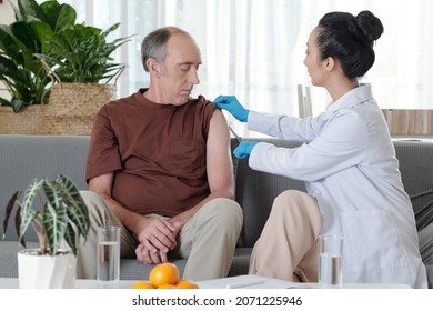 Senior Man Looking At Doctor Cleaning Vaccine Site With Alcohol Based Wash Before Injection