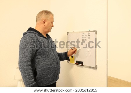 Senior man looking at a flip chart board. Self-directed learning at home, lifelong education, and studying in older age.