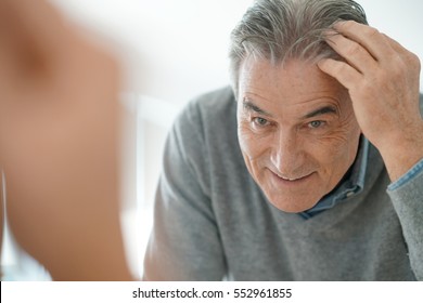 Senior Man Looking At Hair In Mirror