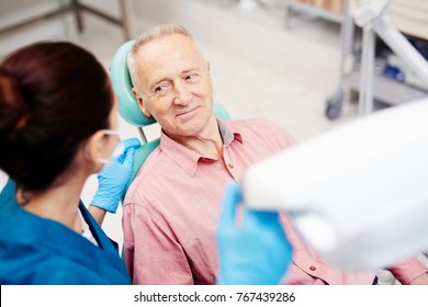 Senior Man Looking At His Dentist And Listening To Her Advice After Oral Check-up