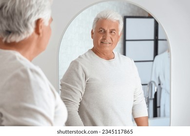 Senior man looking in mirror at home - Powered by Shutterstock