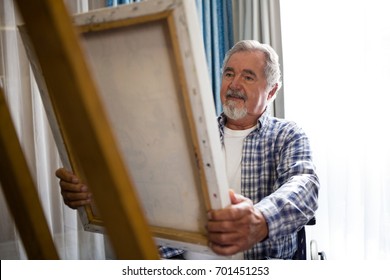 Senior man looking at painting while sitting on wheelchair in nursing home - Powered by Shutterstock