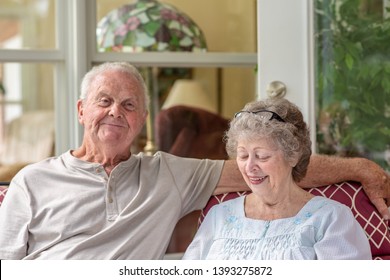 A senior man looks at the camera while his wife looks down. A beautiful senior couple in their seventies spends time together talking on their porch on a sunny day. - Powered by Shutterstock