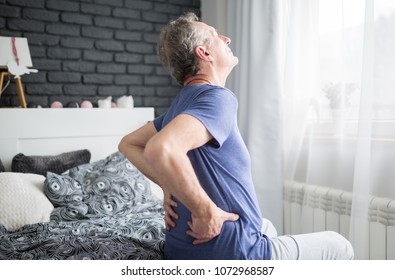 Senior Man With Lower Back Pain Siting On Bed