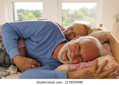 Senior Man Lying Awake In Bed In Morning While His Wife Still Sleeping In Hug