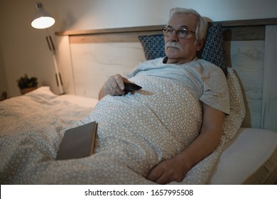 Senior Man Lying Down In Bed And Watching TV At Night. 