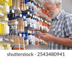 Senior man makes purchases in a hardware store chooses tools for repair or improvement home