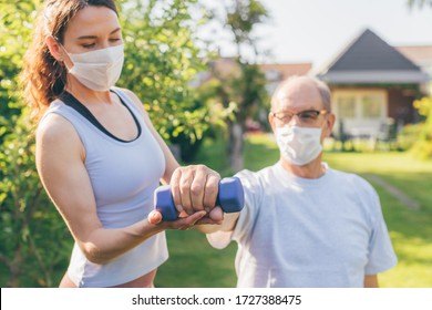 Senior Man Making Physiotherapy Session With Young Doctor (woman) - Concept Of Physical Therapy During Or After Covid-19 Outbreak - Focus On The Hand With Dumbbell