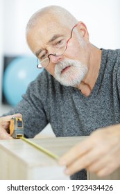 Senior Man Measuring A Furniture