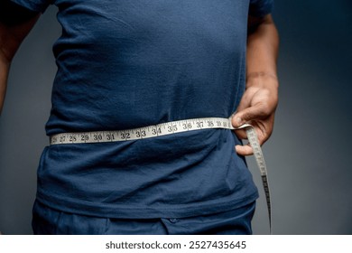 Senior man measuring waist against gray background - Powered by Shutterstock