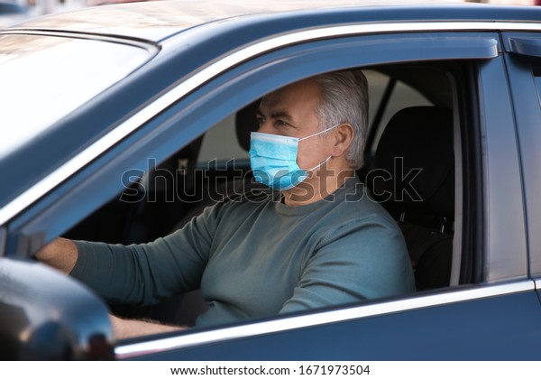 Senior man\
with medical mask in car. Virus\
protection