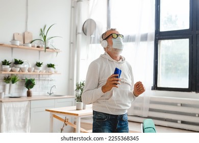 Senior man with medical mask on face dance and using smartphone app for creating playlist music on mobile app - Elderly male having fun dancing with mobile phone technology - Tech and joyful elderly - Powered by Shutterstock