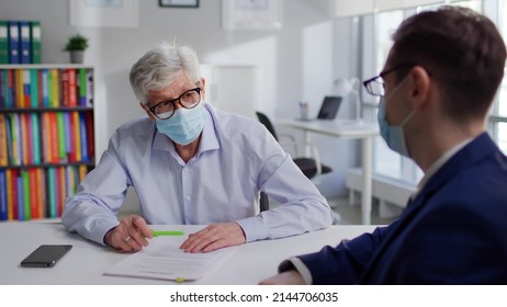 Senior Man In Medical Mask Sign Document In Lawyer Office. Real Estate Agent And Mature Client Signing Rental Agreement