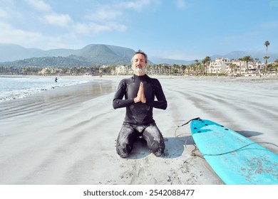 Senior man meditating on the beach before getting into the water to surf the waves - Powered by Shutterstock