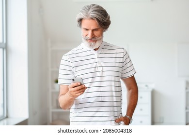 Senior man with mobile phone at home