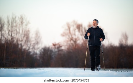 Senior Man Nordic Walking Outdoors On A Snowy, Winter Day