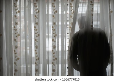 Senior man obeying to curfew looking to empty street from his window - Powered by Shutterstock