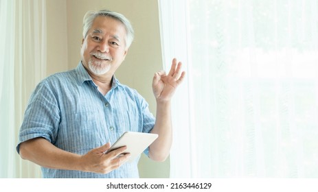 Senior man , old man using a smartphone  , tablet computer and shows ok sign with hands , smiling feel happy in bedroom at home - lifestyle senior using technology concept - Powered by Shutterstock