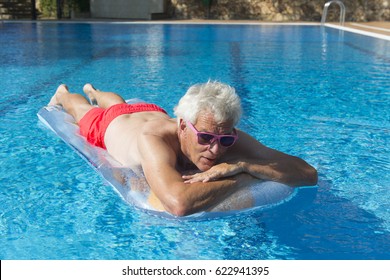 Senior Man On Vacation Floating On Water In Swimming Pool