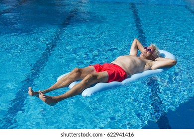 Senior Man On Vacation Floating On Water In Swimming Pool