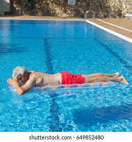 Senior Man On Vacation Floating On Water In Swimming Pool