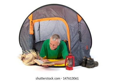 Senior man on vacation and reading laying in tent - Powered by Shutterstock