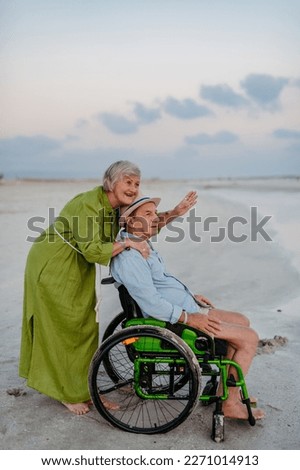Senior man on wheelchair enjoying together time with his wife at sea.