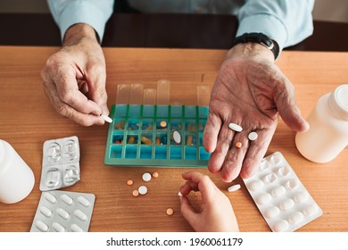 Senior man organizing his medication into pill dispenser. Senior man taking pills from box. Healthcare and old age concept with medicines. Medicaments on table - Shutterstock ID 1960061179