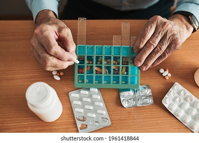 Senior Man Organizing His Medication Into Pill Dispenser. Senior Man Taking Pills From Box. Healthcare And Old Age Concept With Medicines. Medicaments On Table