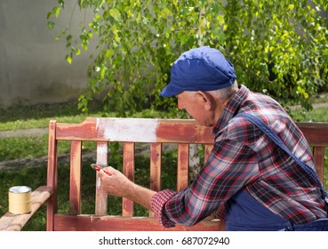 Senior man in overalls painting old bench in park after sandblasting. Repairing old furniture - Powered by Shutterstock