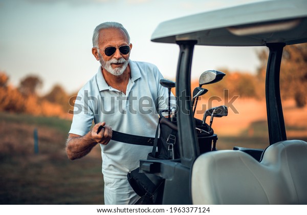 Senior man packs for golf.\
Golf car. 