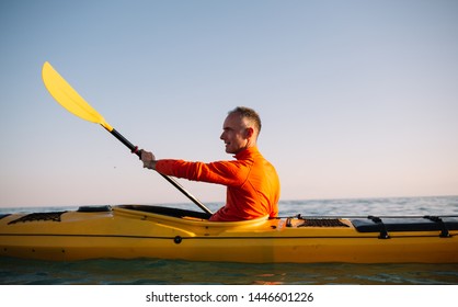 Senior Man Paddling Kayak On The Sunset Sea