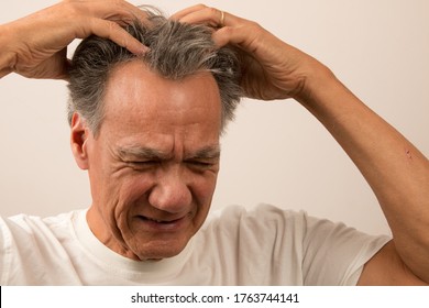 Senior Man In Pain With Headache Massaging The Top Of His Head